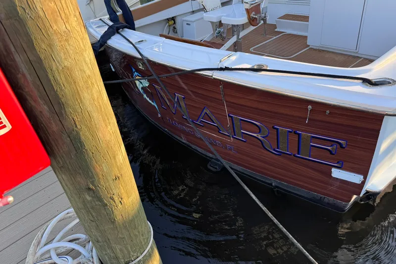 Slide: The Image of 1981 Hatteras 43 Convertible boat docked, featuring wooden detailing and name "Marie." - 83
