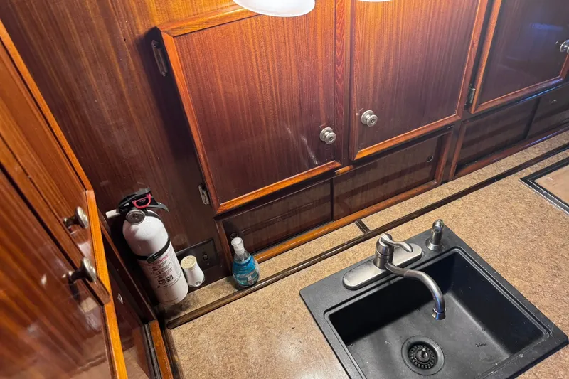 Slide: The Image of 1981 Hatteras 43 Convertible kitchen with sink, wooden cabinets, and fire extinguisher. - 29