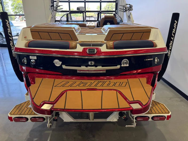 Slide: The Image of The image shows the rear of a 2021 Malibu Wakesetter 23 LSV. It features a red and white finish with a spacious deck and brown upholstery. - 7