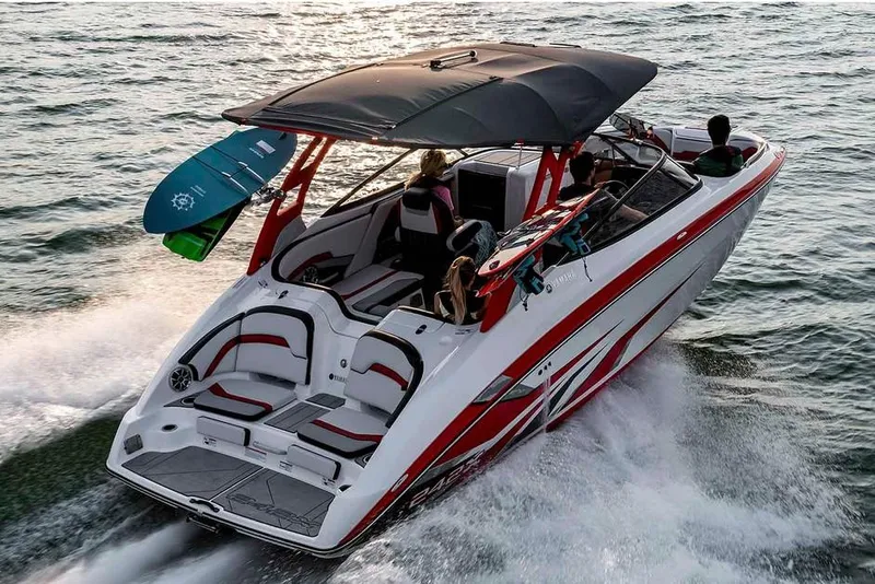 Slide: The Image of A 2020 Yamaha 242X boat speeds across the water. It features a modern design with red accents and a sunshade. - 17