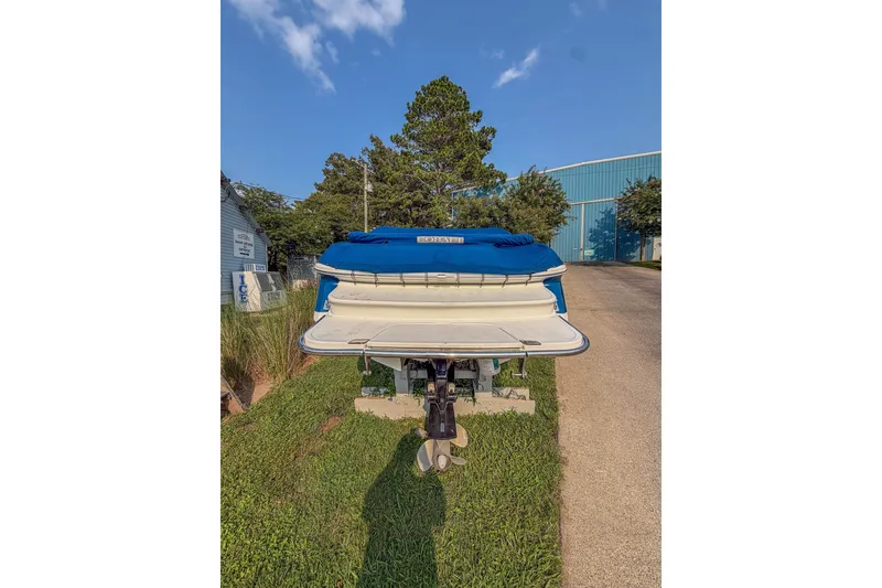 Slide: The Image of 2011 Cobalt 210 boat with blue cover, parked on grass near a building. - 3