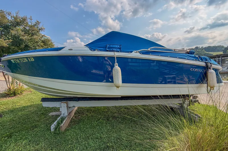 Slide: The Image of 2011 Cobalt 210 boat on trailer, blue cover, grassy area, sunny day. - 5