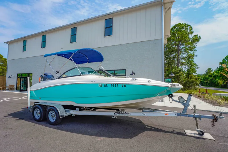 The Image of 2020 NauticStar 203 DC boat on trailer, parked outside a building. - 1
