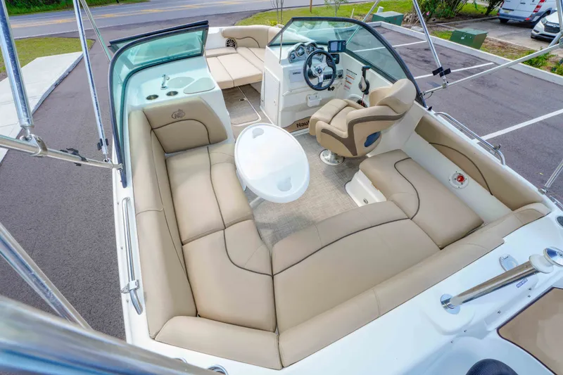Slide: The Image of 2020 NauticStar 203 DC boat interior with beige seating, steering console, and round table. - 13