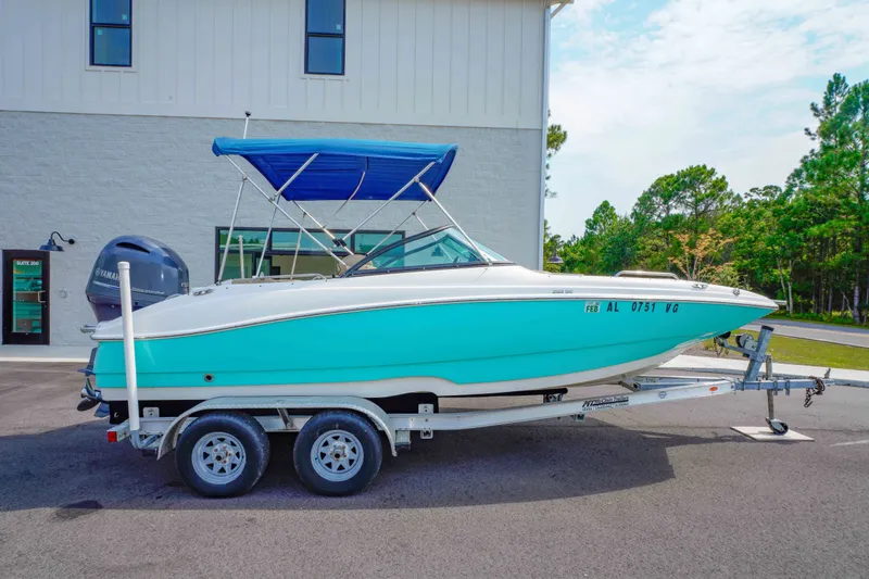 Slide: The Image of 2020 NauticStar 203 DC boat on trailer with blue canopy, parked outdoors. - 2