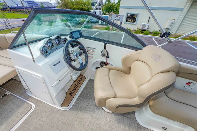 Slide: The Image of 2020 NauticStar 203 DC boat interior with steering wheel and beige captain's chair. - 16