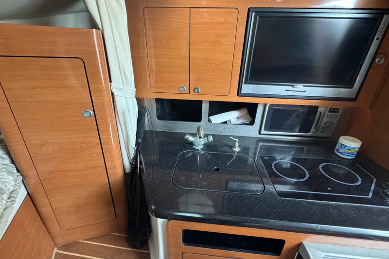 Slide: The Image of 2008 Century 3200 Offshore boat interior with kitchenette, featuring stove, sink, and microwave. - 30