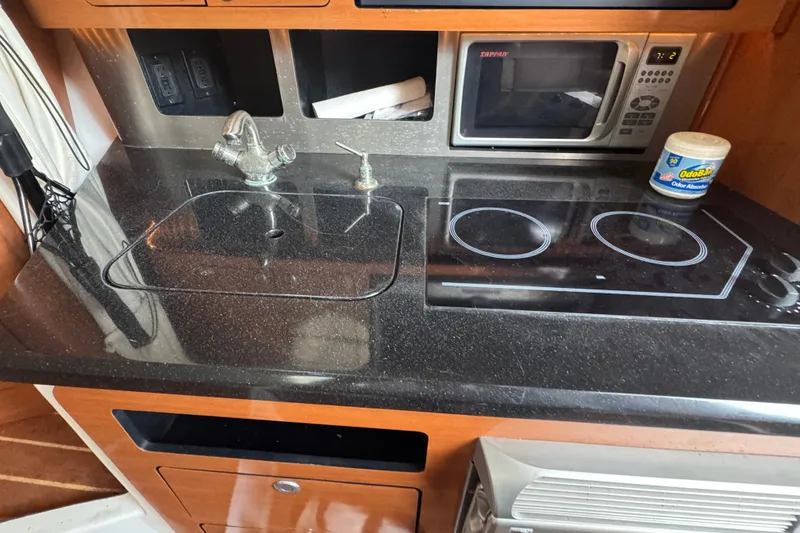 Slide: The Image of Compact kitchen area in a 2008 Century 3200 Offshore boat with sink, stove, and microwave. - 23