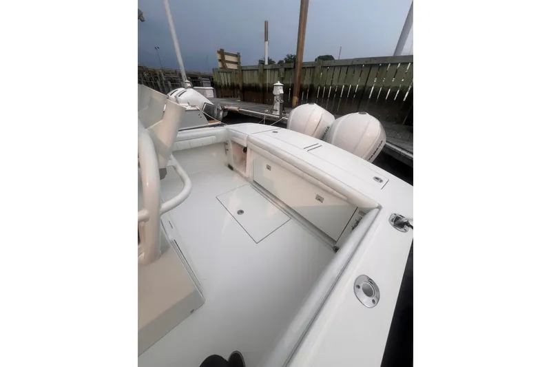 Slide: The Image of 2019 Regulator 28 Forward Seating boat interior with dual engines, docked by wooden fence. - 6