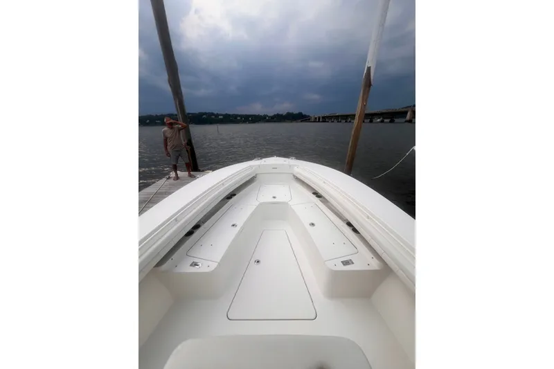 Slide: The Image of 2019 Regulator 28 Forward Seating boat docked on a cloudy day, with bridge in background. - 7