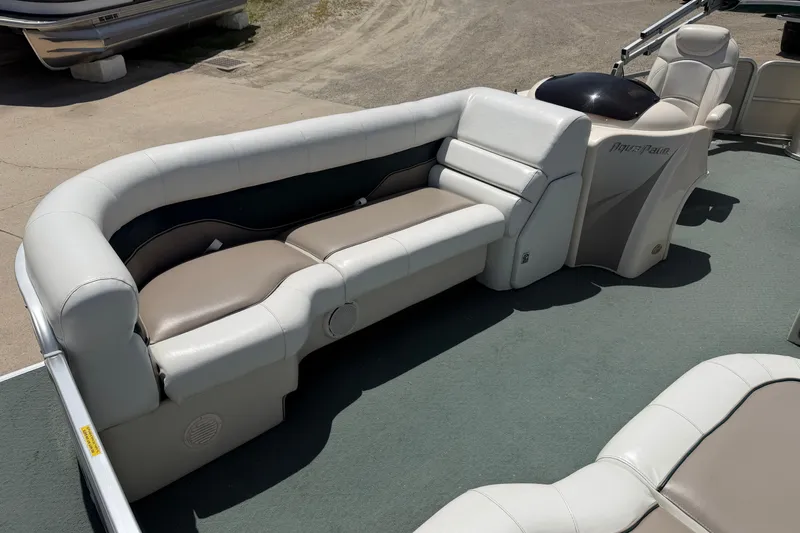 Slide: The Image of 2006 Godfrey Aqua Patio boat interior with beige and white seating on green carpet. - 5