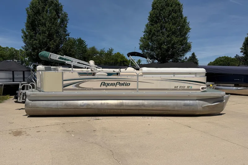 Slide: The Image of 2006 Godfrey Aqua Patio pontoon boat parked on concrete with trees in the background. - 1