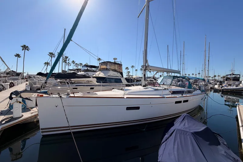 Slide: The Image of 2014 Jeanneau Sun Odyssey 469 sailboat docked at a marina under clear blue skies. - 1