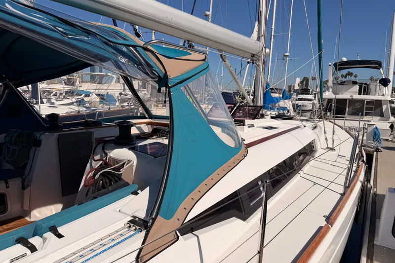 Slide: The Image of 2014 Jeanneau Sun Odyssey 469 sailboat docked at marina, featuring blue canopy and sleek design. - 13