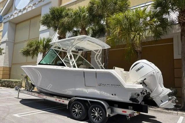 Slide: The Image of 2027 Sailfish 276 DC boat on trailer with Yamaha engine, parked near palm trees. - 1
