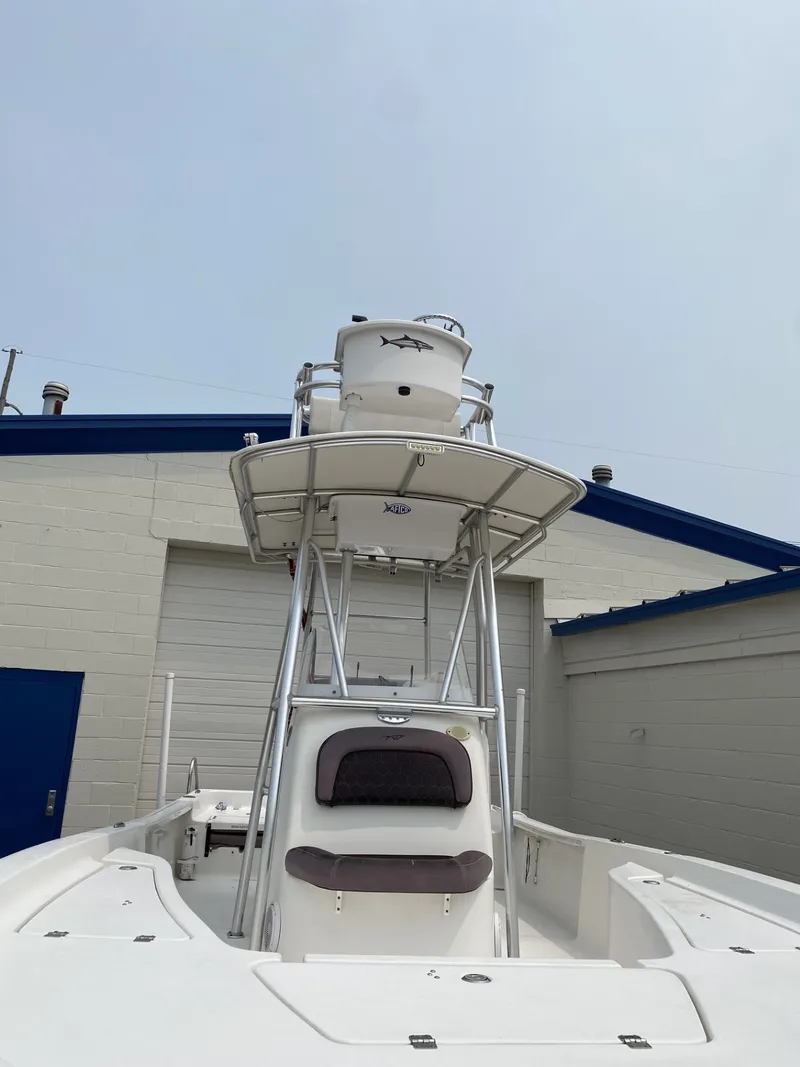 Slide: The Image of A 2018 Tidewater 22 Bay boat with elevated helm station, parked in front of a building. - 2