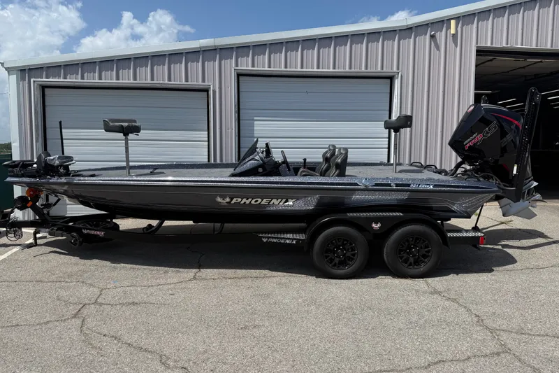 Slide: The Image of 2027 Phoenix 921 Elite X boat parked outside a garage on a sunny day. - 1