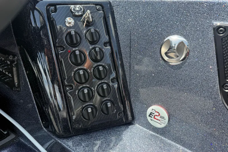 Slide: The Image of Control panel of 2027 Phoenix 921 Elite X boat with switches and metallic finish. - 17