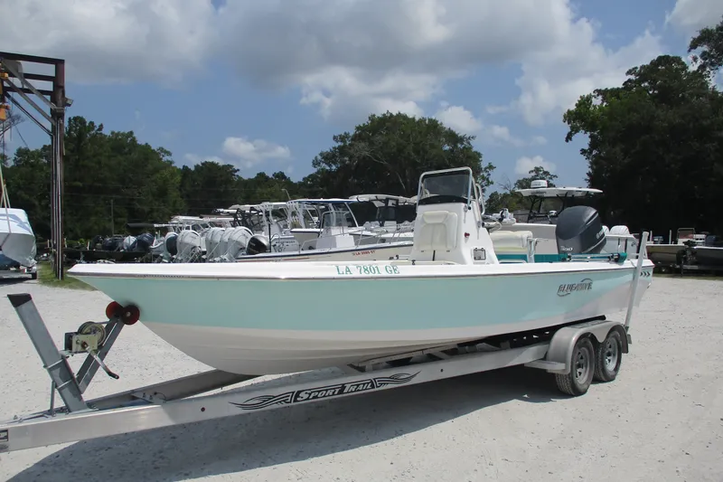 Slide: The Image of 2016 BLUEWAVE 24 Pure Bay boat on trailer, parked outdoors under cloudy sky. - 2