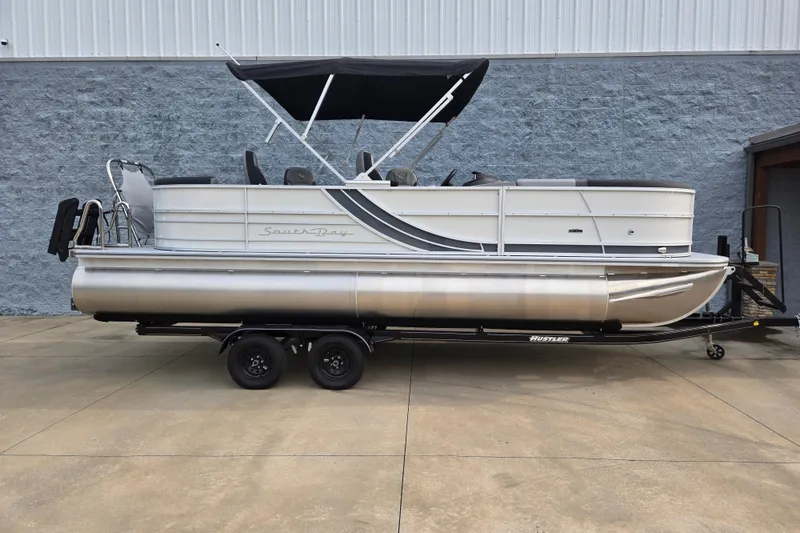 The Image of A 2027 South Bay SS224QC3.O pontoon boat on a trailer, featuring a black sunshade. - 1