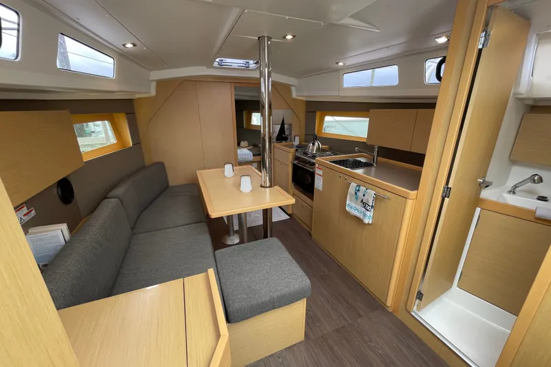 Slide: The Image of 2016 Beneteau Oceanis 35 interior with modern kitchen, dining area, and wood finishes. - 23