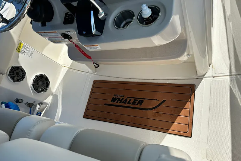 Slide: The Image of Interior view of 2024 Boston Whaler 250 Outrage boat, featuring helm and branded mat. - 15