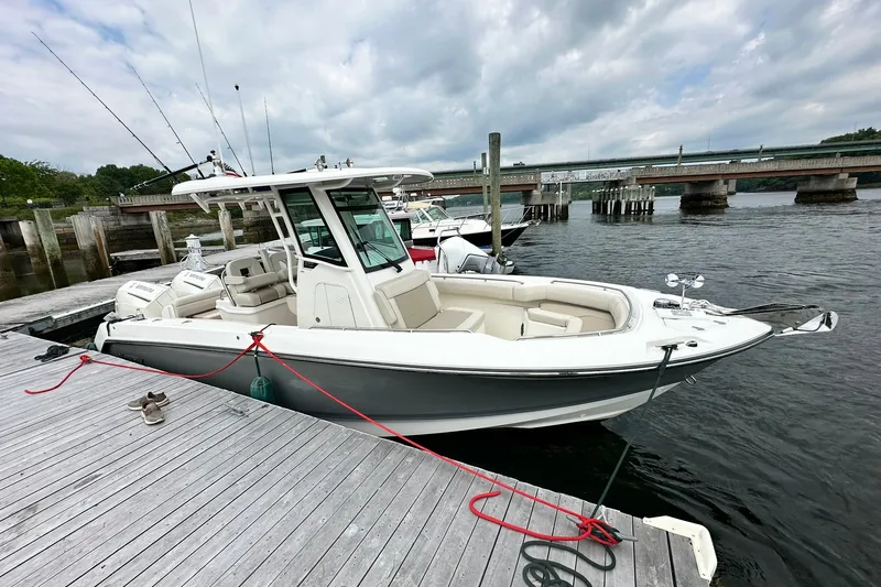 Slide: The Image of 2024 Boston Whaler 250 Outrage docked by a wooden pier under cloudy skies. - 7