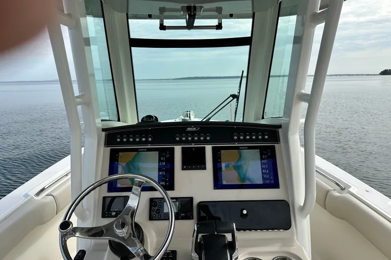 Slide: The Image of 2024 Boston Whaler 250 Outrage helm with dual navigation screens on calm water. - 8