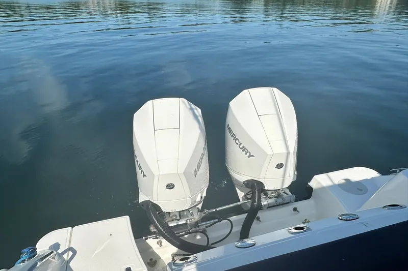 Slide: The Image of 2024 Boston Whaler 250 Outrage with twin Mercury outboard engines on calm water. - 25