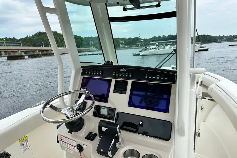 Slide: The Image of 2024 Boston Whaler 250 Outrage helm with advanced navigation system on a calm waterway. - 10