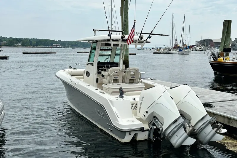 Slide: The Image of 2024 Boston Whaler 250 Outrage docked, featuring dual Mercury engines, in a scenic marina setting. - 6