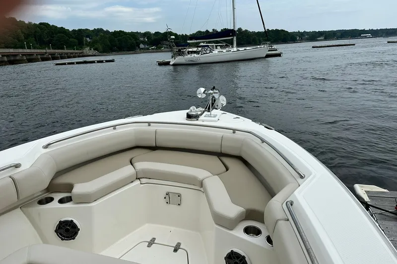 Slide: The Image of 2024 Boston Whaler 250 Outrage boat interior with seating, docked on a calm lake. - 21