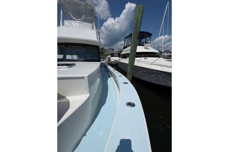 Slide: The Image of 2023 Millenium 37 Walk Around Fly Bridge Sportfish docked at marina under blue sky. - 14