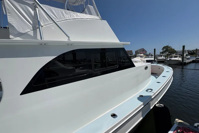 Slide: The Image of 2023 Millenium 37 Walk Around Fly Bridge Sportfish docked at a marina under clear skies. - 48