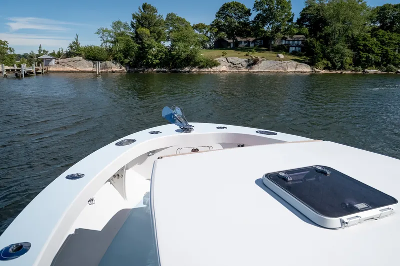 Slide: The Image of 2023 Millennium Marine 37 Walk Around Fly Bridge Sportfish on calm waters near a scenic shoreline. - 73