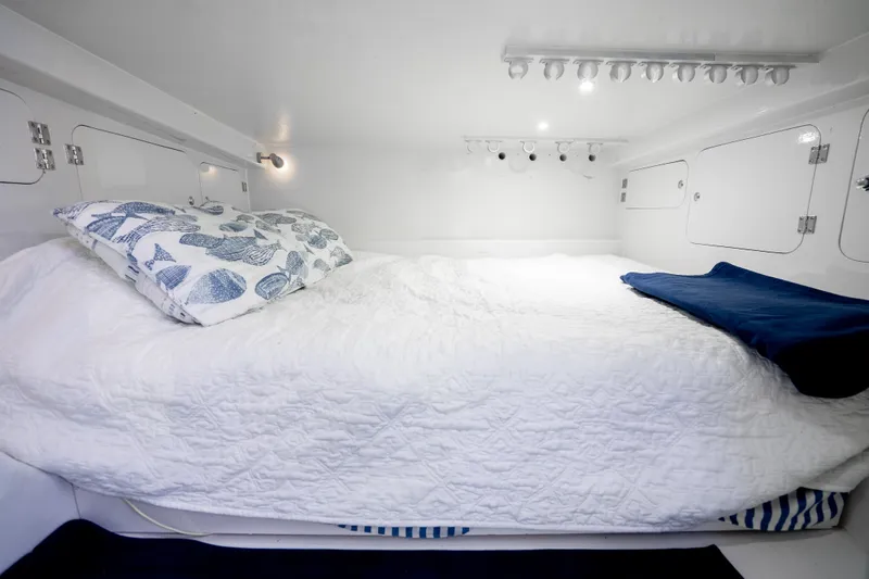 Slide: The Image of 2023 Millennium Marine 37 Walk Around Fly Bridge Sportfish cabin with cozy bed and nautical decor. - 95