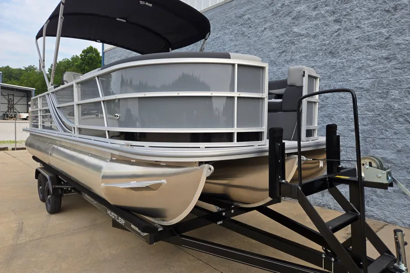 Slide: The Image of A modern pontoon boat with a gray hull and black canopy sits on a trailer. - 3