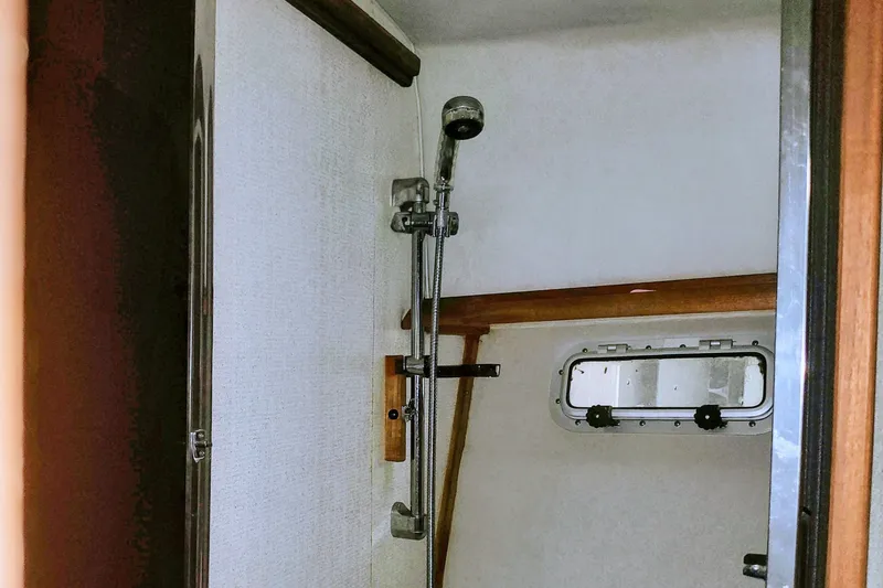 Slide: The Image of The shower in the 1988 Bayliner 3818 Motoryacht features a handheld showerhead and a porthole. - 49