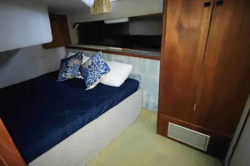Slide: The Image of The 1988 Bayliner 3818 Motoryacht cabin features a cozy bed with blue pillows. - 35