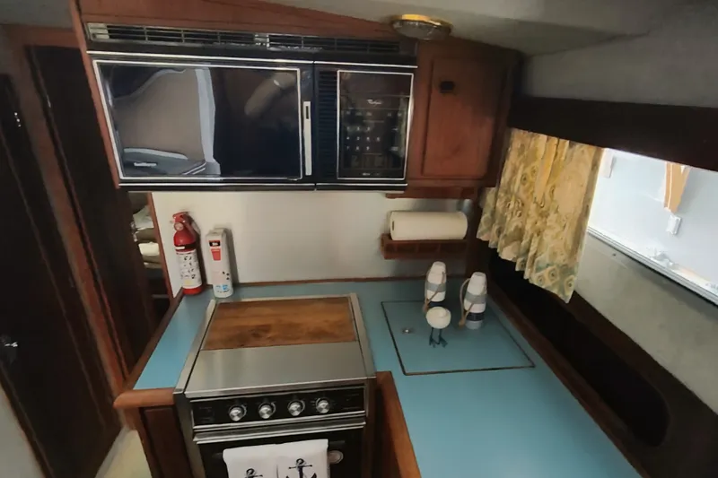 Slide: The Image of 1988 Bayliner 3818 Motoryacht kitchen with stove, microwave, and wooden cabinetry. - 31