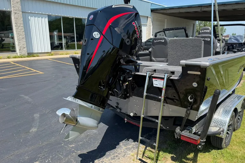 Slide: The Image of 2027 Lund 1875 Pro-V boat with powerful outboard motor and trailer in a parking lot. - 2