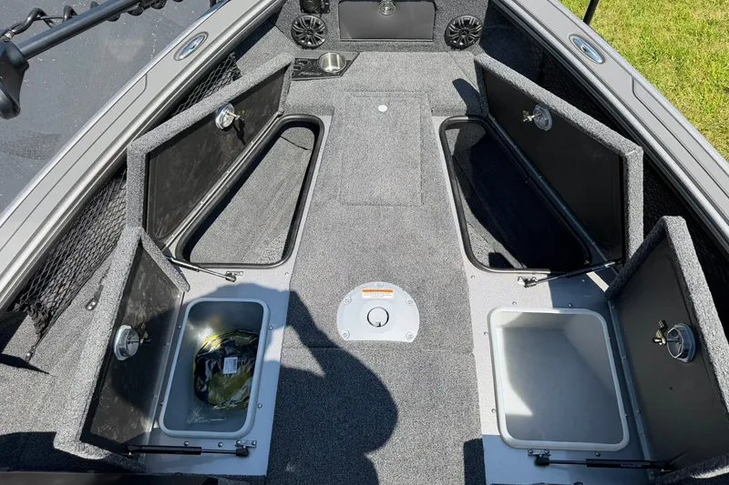 Slide: The Image of 2027 Lund 1875 Pro-V boat interior with open storage compartments and carpeted flooring. - 18