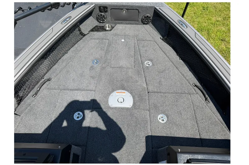 Slide: The Image of 2027 Lund 1875 Pro-V boat interior with gray carpet and storage compartments. - 16