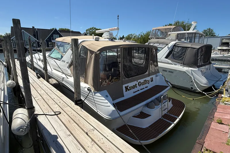 Slide: The Image of 1996 Sea Ray 400 Express Cruiser docked at marina, featuring tan canopy and wooden deck. - 2