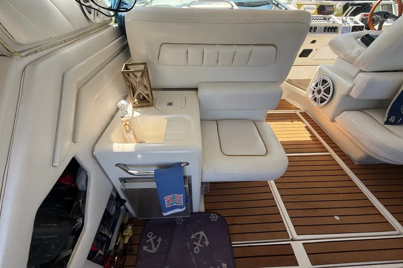 Slide: The Image of 1996 Sea Ray 400 Express Cruiser interior with white seating, wooden flooring, and compact sink area. - 15