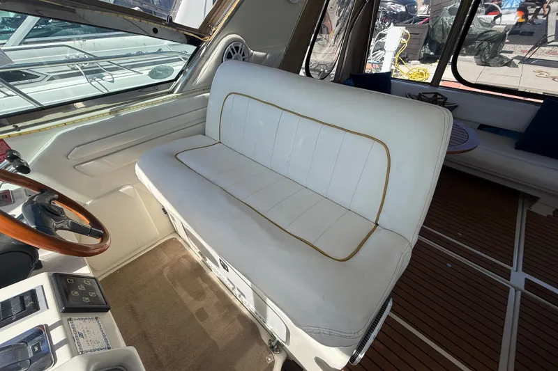 Slide: The Image of Interior of 1996 Sea Ray 400 Express Cruiser with white seating and wooden steering wheel. - 18