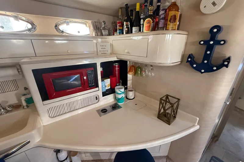 Slide: The Image of 1996 Sea Ray 400 Express Cruiser galley with red microwave, drinks, and nautical decor. - 30