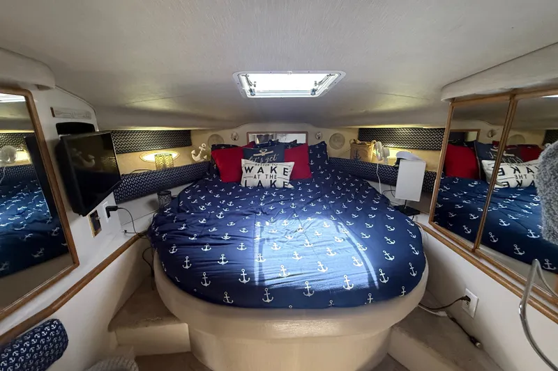 Slide: The Image of 1996 Sea Ray 400 Express Cruiser cabin with nautical-themed bedding and cozy interior. - 35