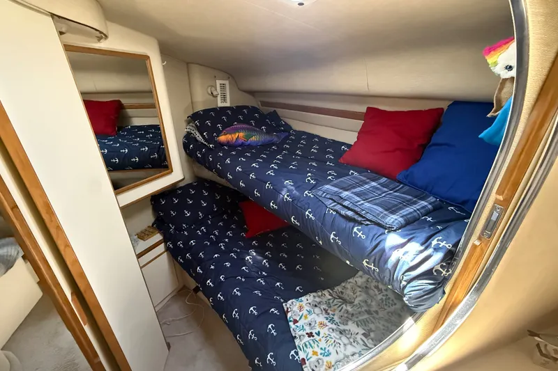 Slide: The Image of 1996 Sea Ray 400 Express Cruiser cabin with bunk beds, nautical-themed bedding, and colorful pillows. - 32