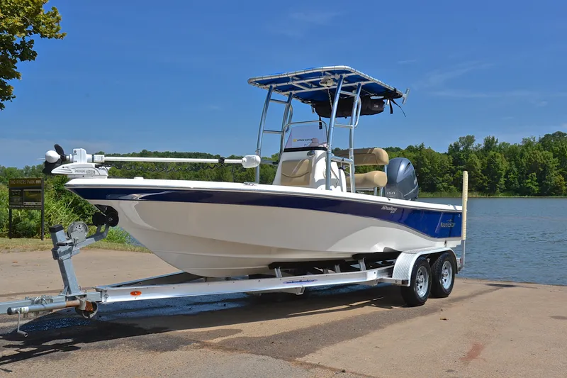 Slide: The Image of 2019 NauticStar 215 XTS Shallow Bay boat on trailer by a lake. - 10